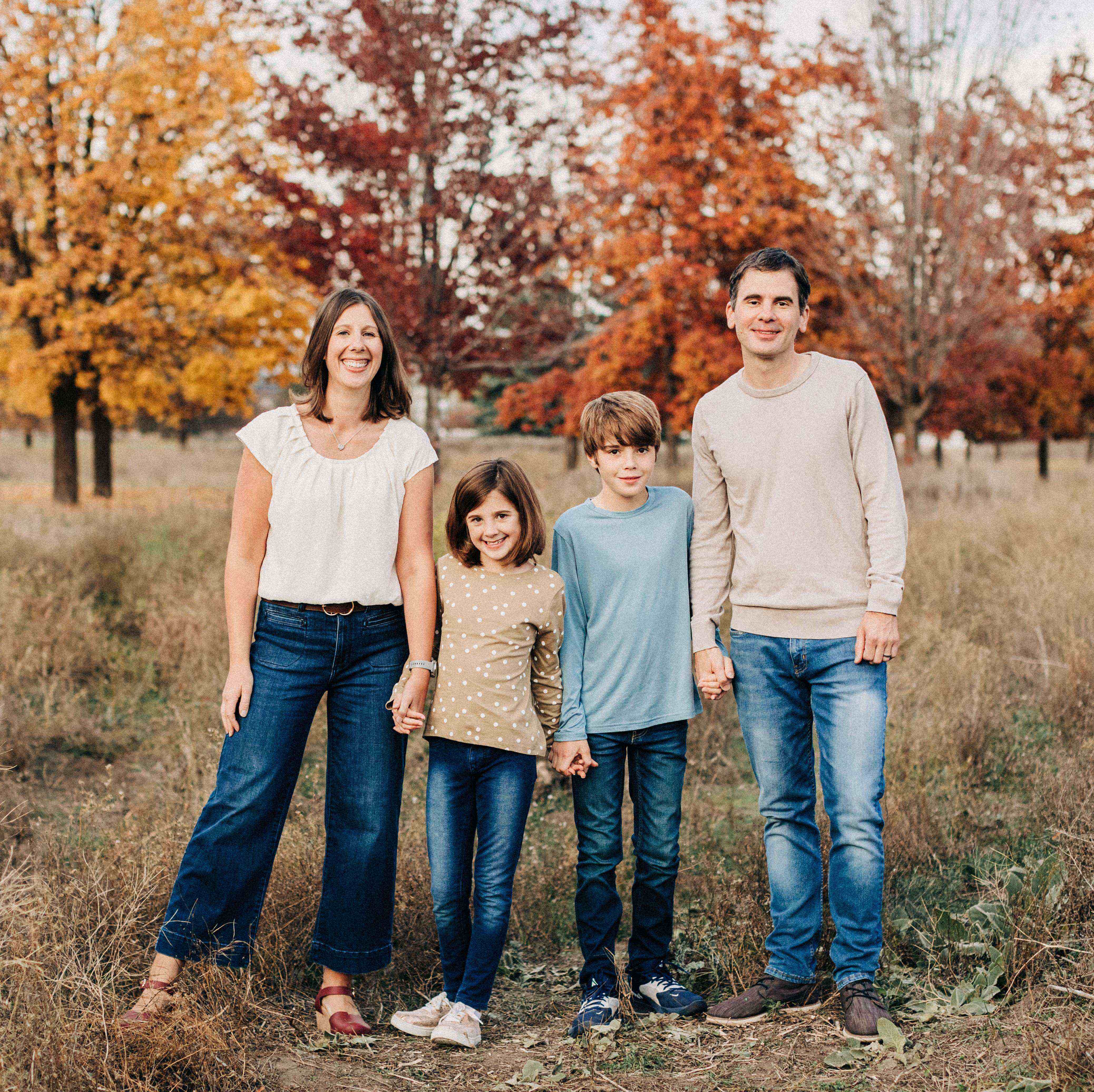 family of four standing in front of fall trees