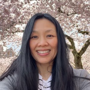 Smiling woman in front of cherry tree blossoms