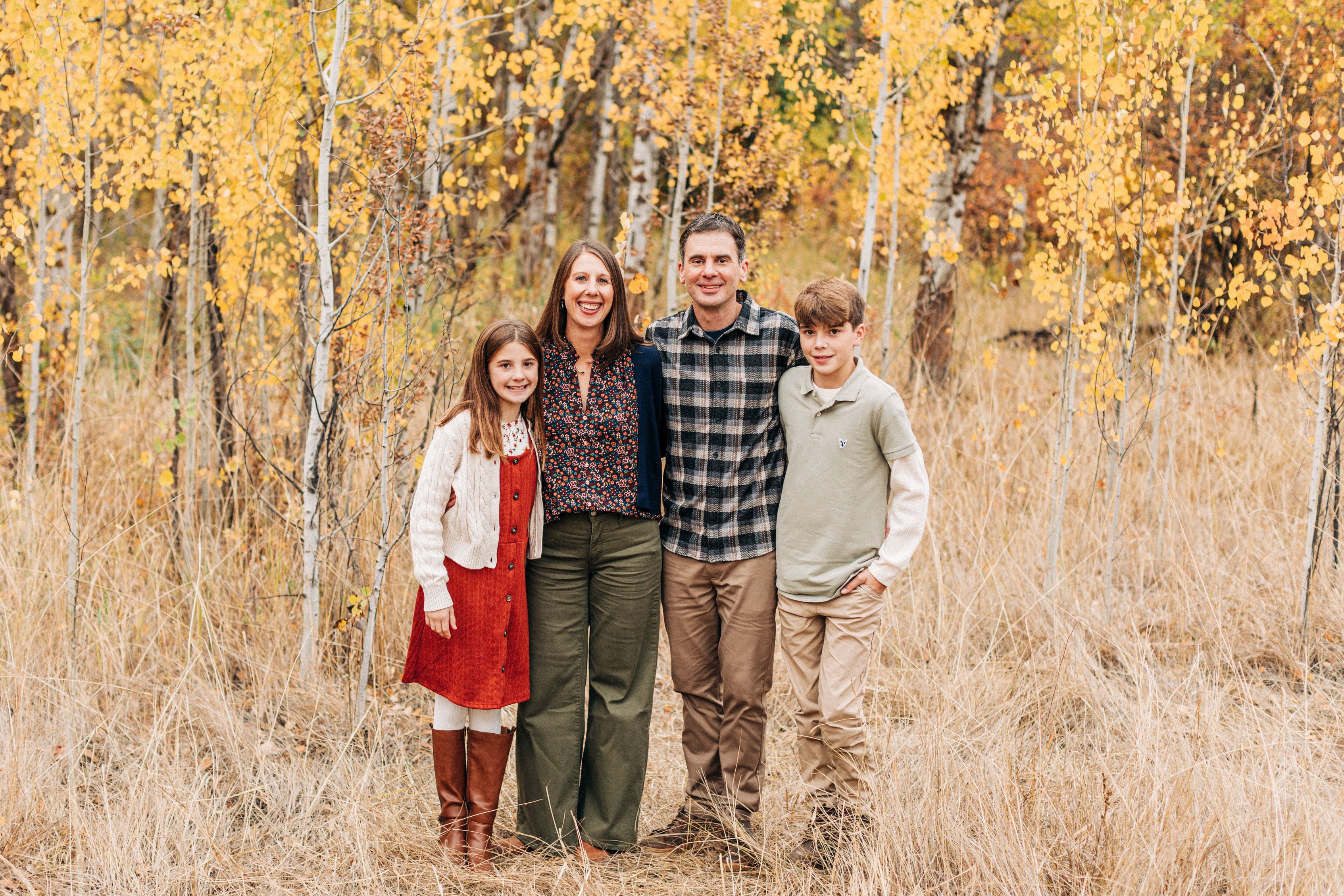 family of four in front of fall tress