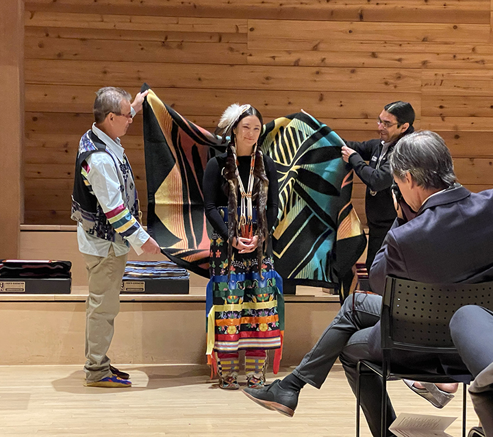 UW School of Medicine graduating student being draped by a Native American blanket.