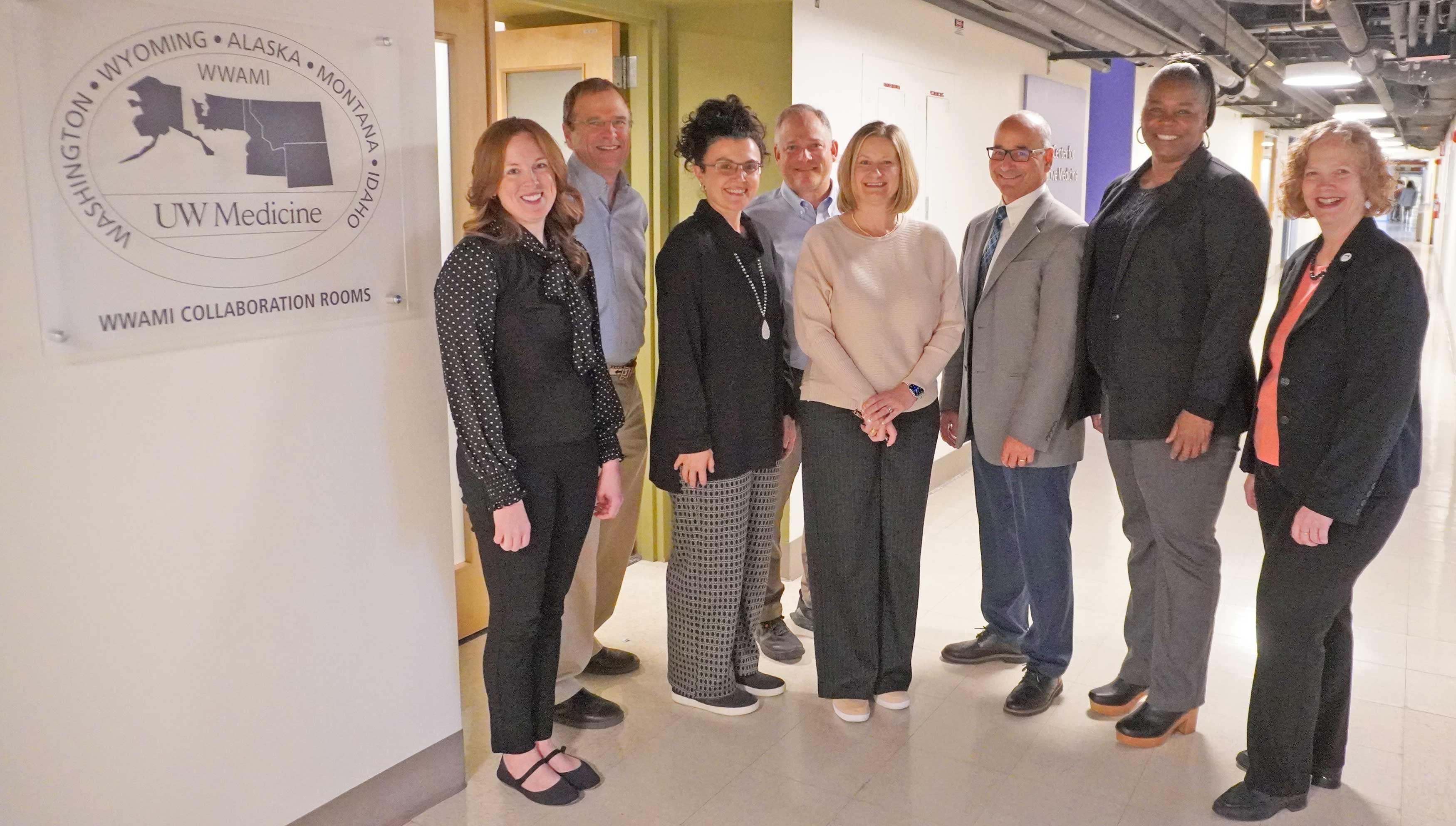 individuals named in the caption standing in a hallway by a WWAMI collaboration sign 