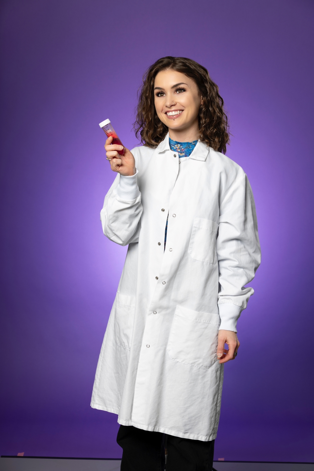 Shyanne King holds a vial of red liquid while wearing a white lab coat