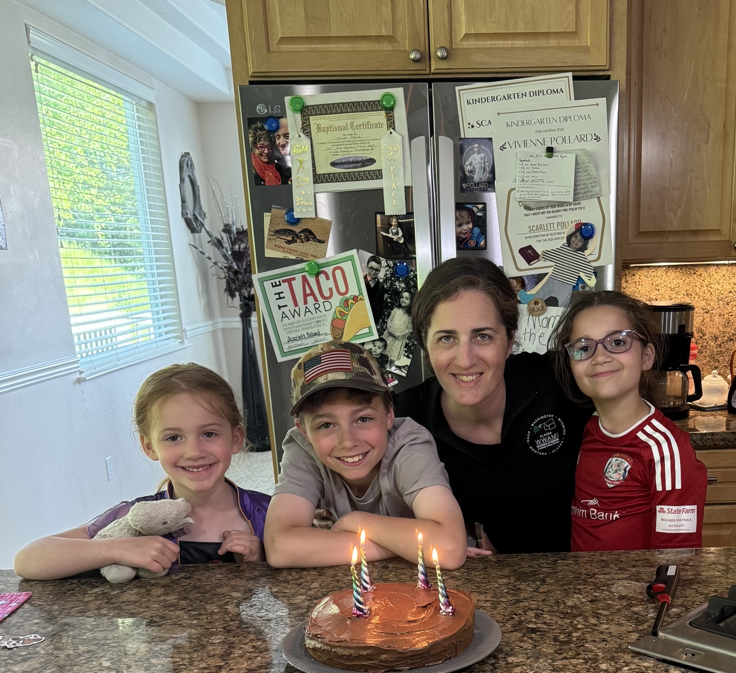Heather Pollard and her children pose in front of a homemade birthday cake in the kitchen
