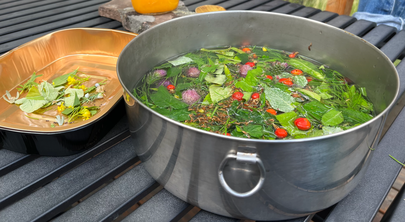 A large silver bowl full of herbs being boiled for tea