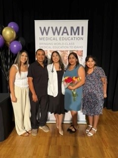 Kenya Morales poses with her family in front of a WWAMI poster