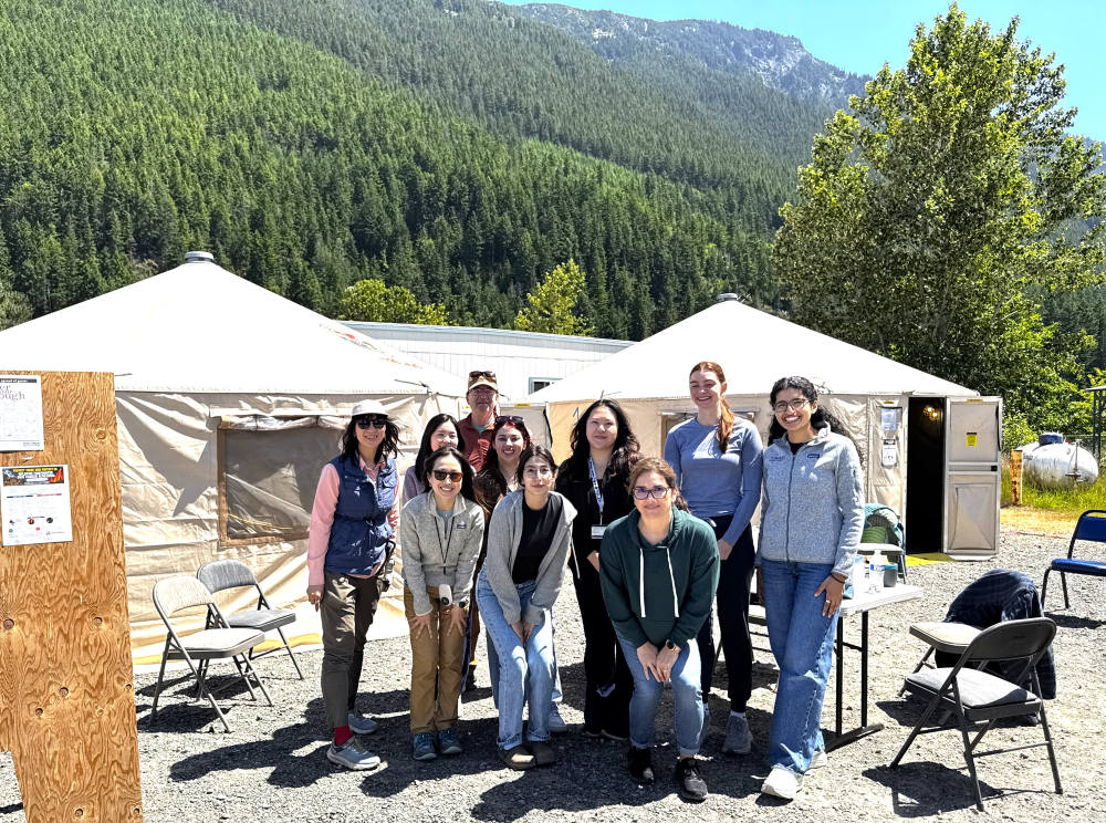 A group of volunteers poses in front of white tents