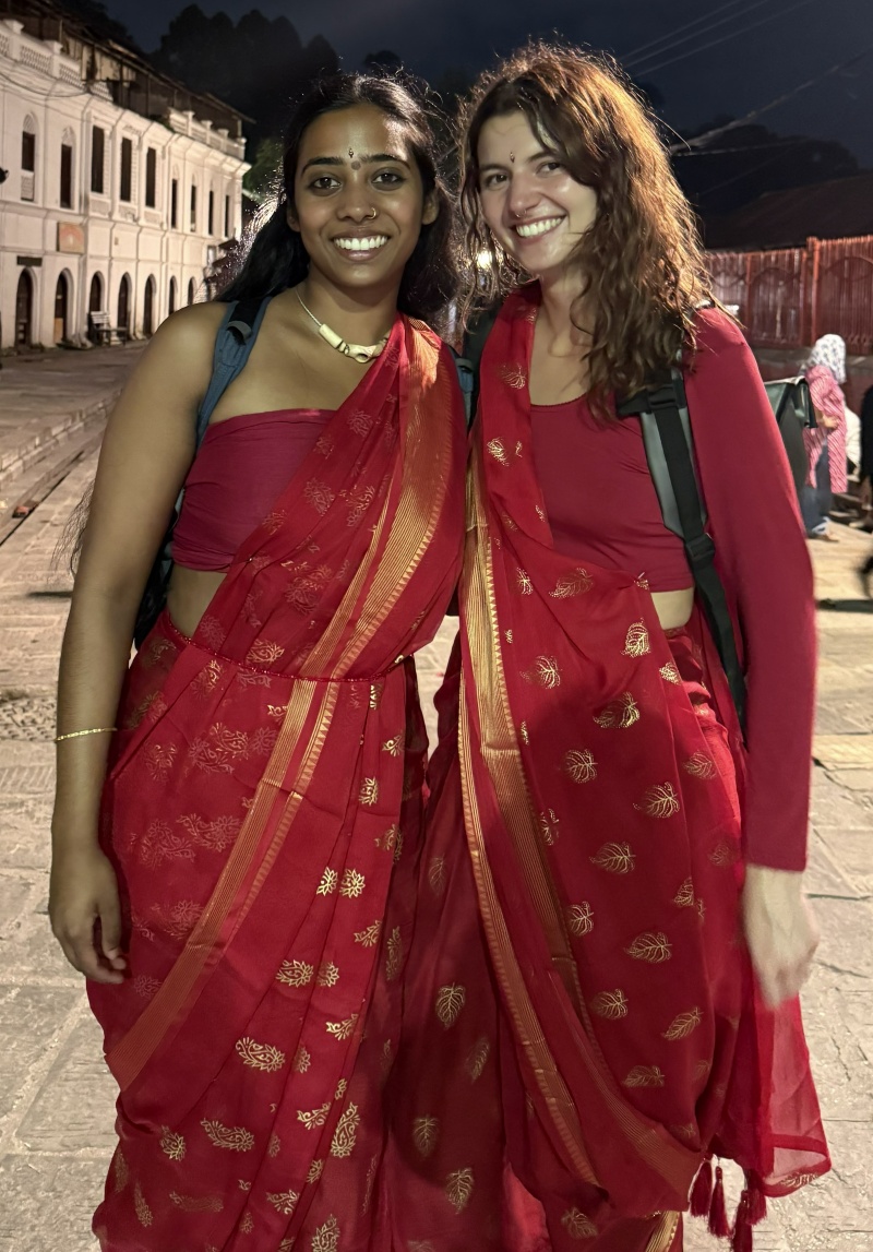 Lindsey Downie and Bhargavi Pochi pose together in red saris