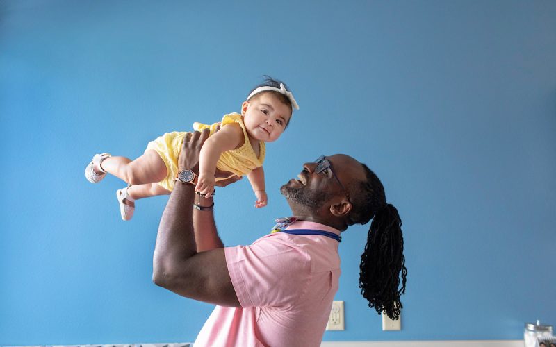 dr asante holding a baby in the air