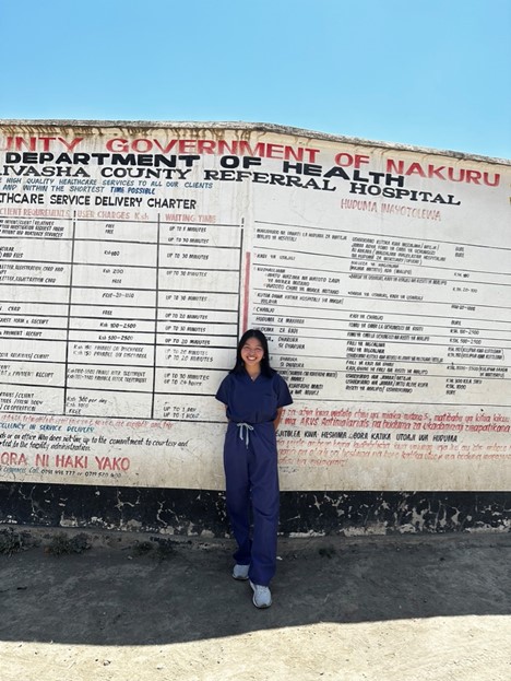 Pham standing in front of the office front sign in Kenya